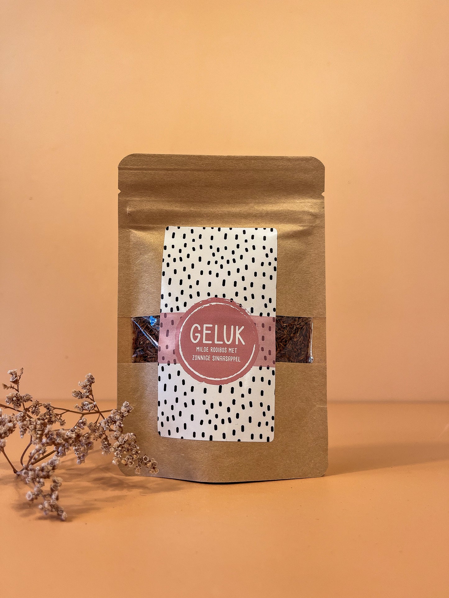 Kartonnen zakje met losse rooibos thee. De naam van de thee is: geluk. De smaak is rooibos met sinaasappel.