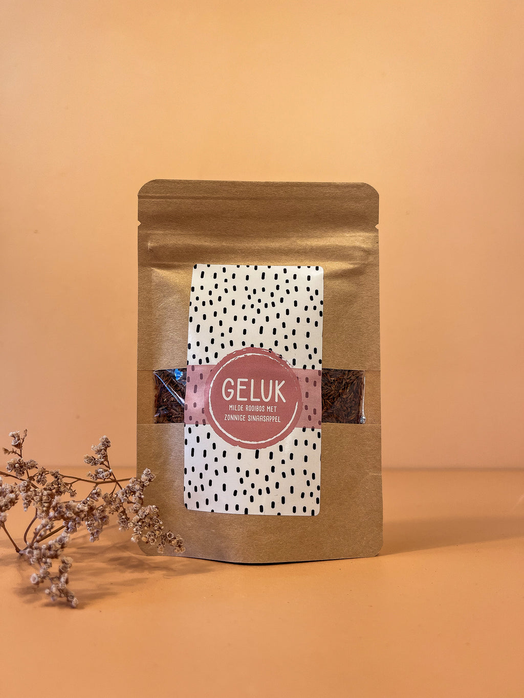 Kartonnen zakje met losse rooibos thee. De naam van de thee is: geluk. De smaak is rooibos met sinaasappel.